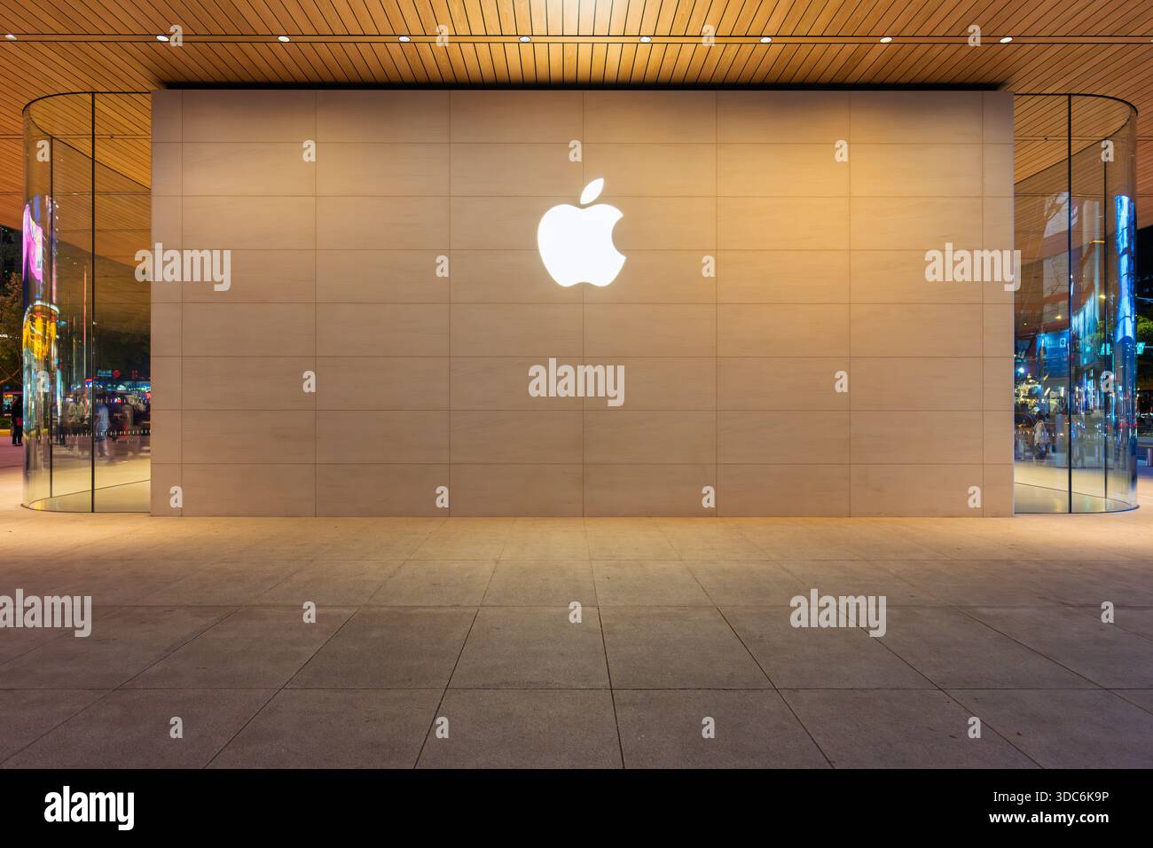 Taipei, Taiwan - 20 dicembre 2025: Esterno dell'Apple Store con logo illuminato e facciata in vetro curvo, i clienti sono visibili all'interno Foto Stock