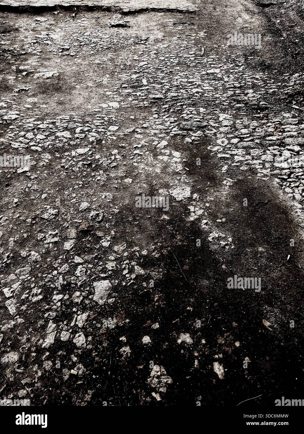 Sfondo grunge di asfalto rotto. Una vecchia strada in rovina con difetti in bianco e nero. Foto Stock