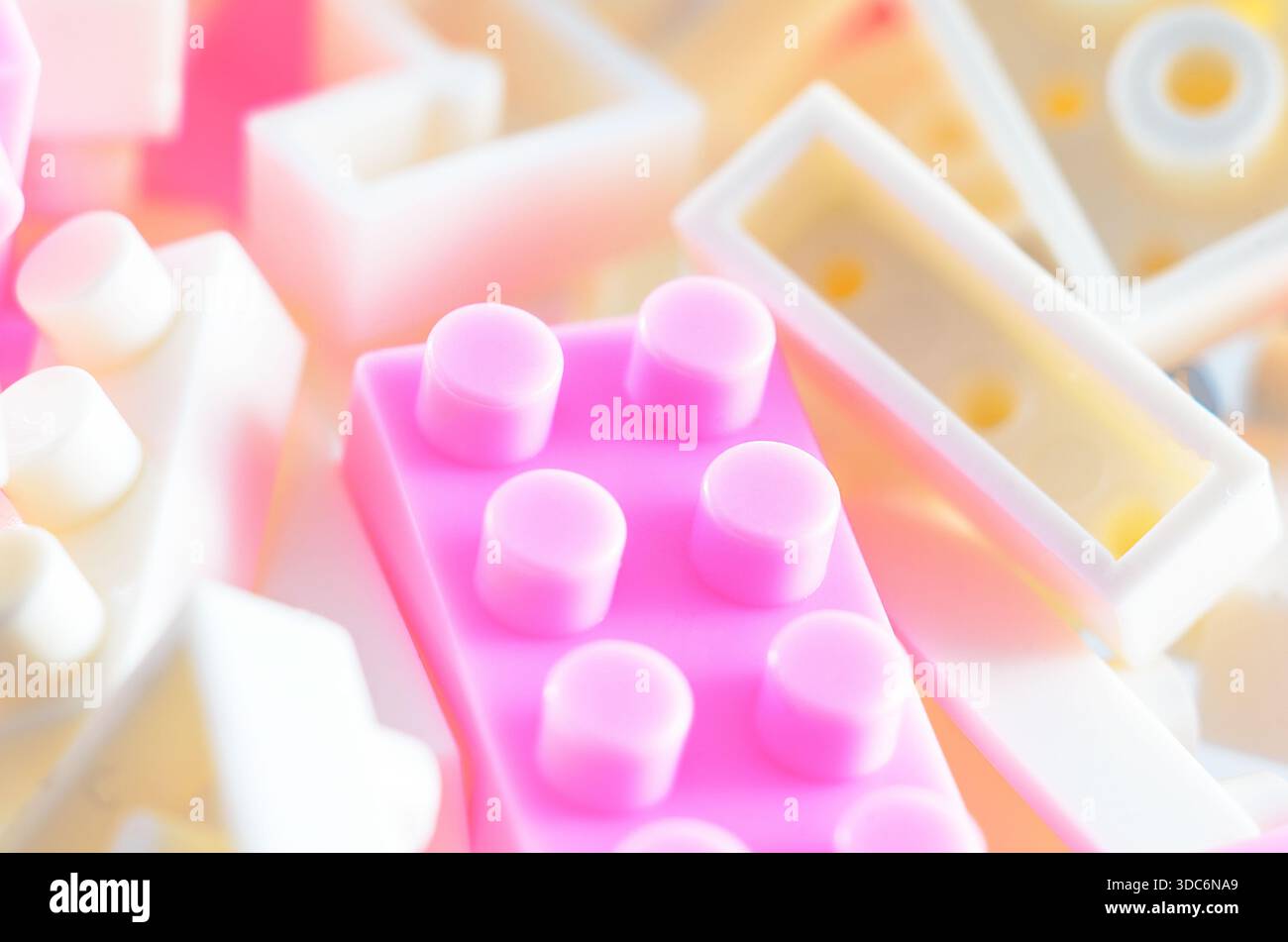 Una collezione di blocchi da costruzione rosa pastello e bianco sono disposti in una delicata messa a fuoco, creando un'atmosfera sognante e giocosa per una costruzione creativa Foto Stock