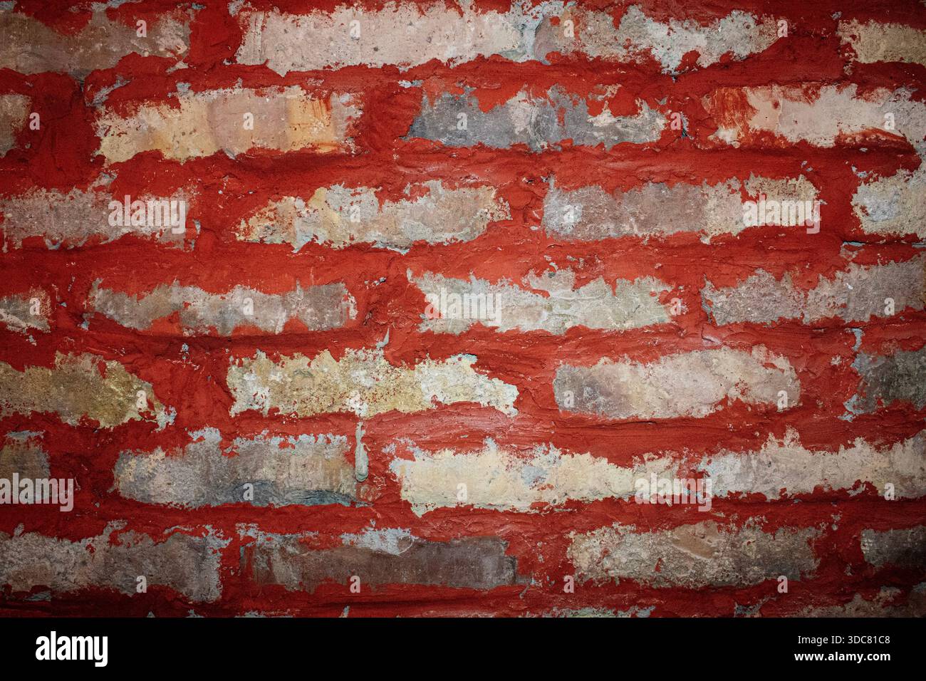 Foto ad alta risoluzione di una parete in mattoni verniciati di rosso con tratti di pennello visibili e superfici usurate, adatta per applicazioni urbane, industriali e di design b Foto Stock