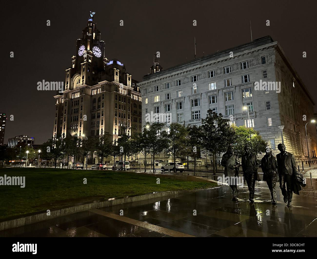 La statua dei Beatles a Pier Head, Liverpool, figure di bronzo illuminate sotto l'iconica architettura del lungomare in una notte serena Foto Stock