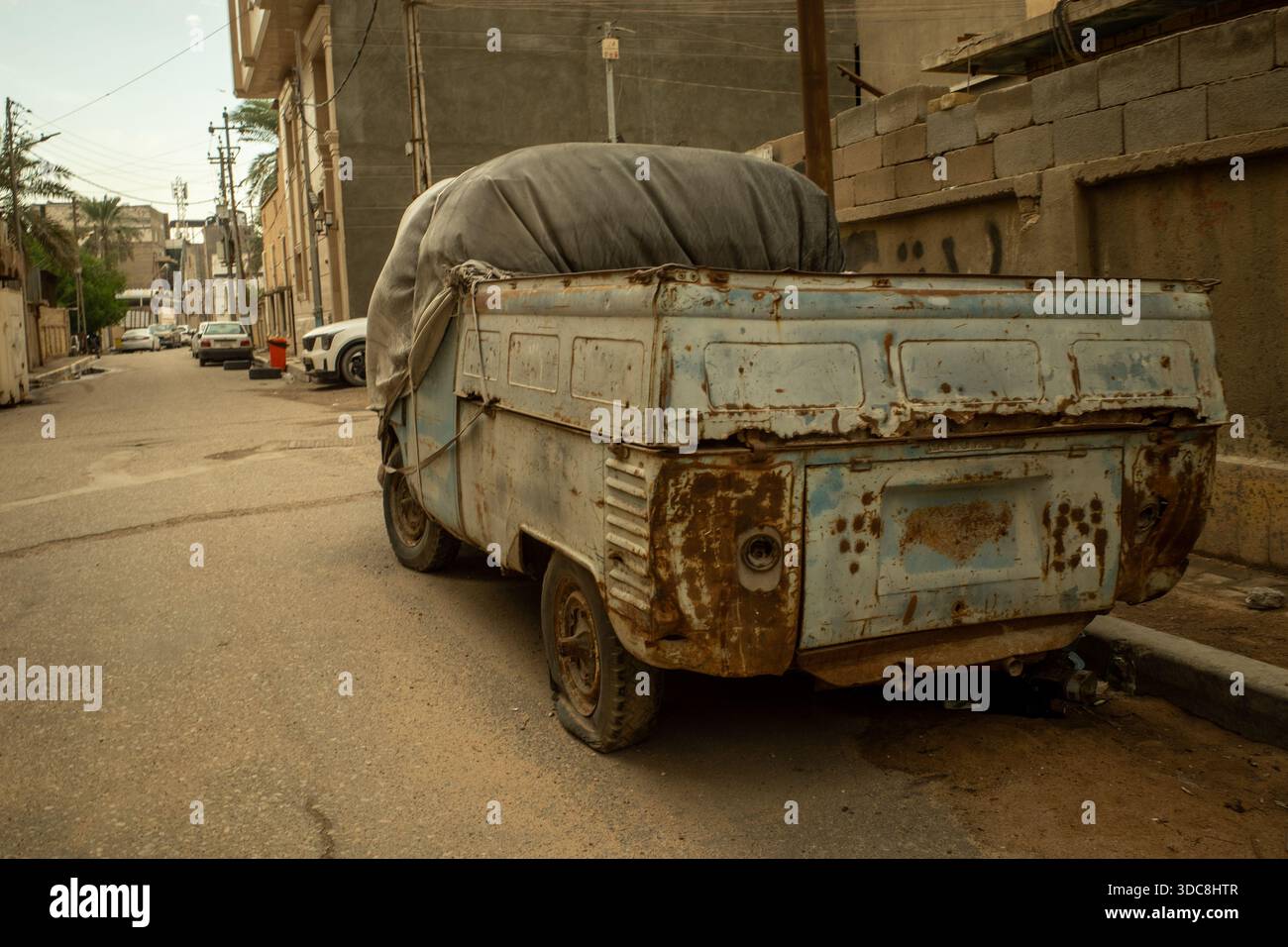 Ampia corrosione atmosferica e formazione di ossido ferrico su un pick-up Volkswagen Transporter blu d'epoca in un ambiente urbano Foto Stock