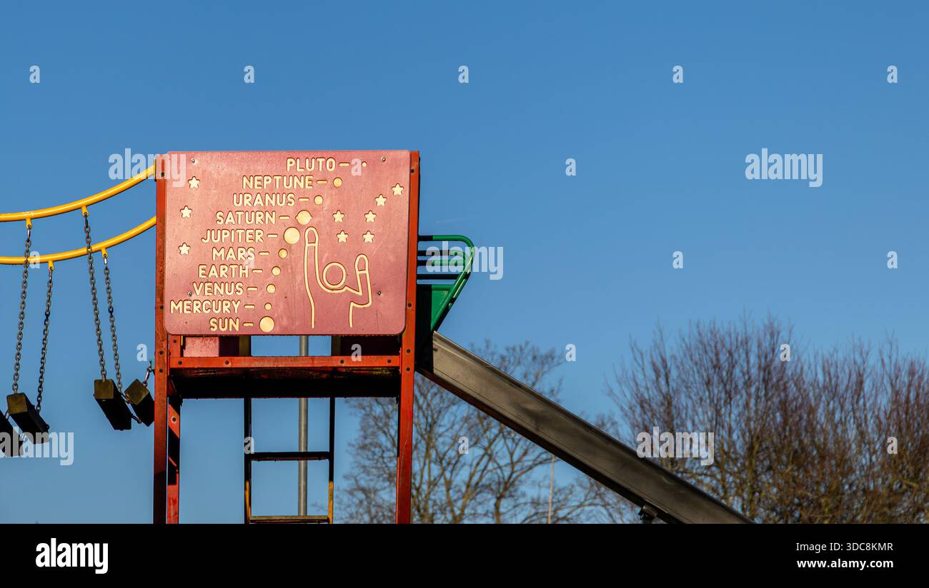 Colorato parco giochi caratterizzato da un sistema solare a tema con nomi di pianeti e uno scivolo sotto un cielo azzurro Foto Stock