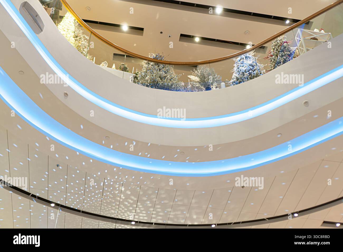 Atrio moderno a tre livelli, inondato di luce naturale soffusa, decorato con soffitto astratto, lampadari, decorazioni natalizie, mobili trasparenti Foto Stock