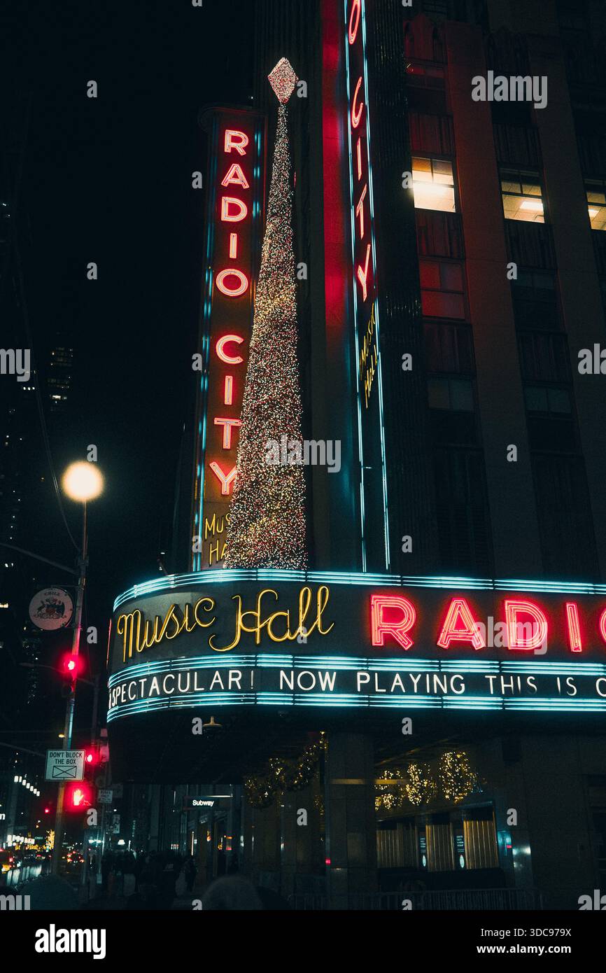 Radio City Music Hall illuminata di notte con segnaletica al neon illuminata lungo la Sixth Avenue a Midtown Manhattan, New York City. Foto Stock
