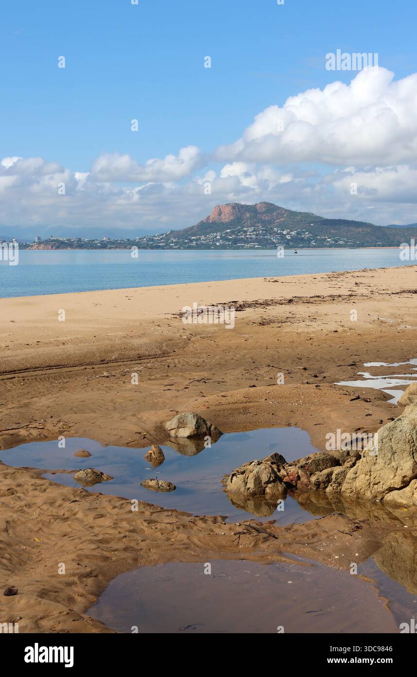 Spiaggia con sabbia, pozzanghere d'acqua e l'oceano con Castle Hill sullo sfondo a Cape Pallarenda a Townsville, Queensland, Australia Foto Stock
