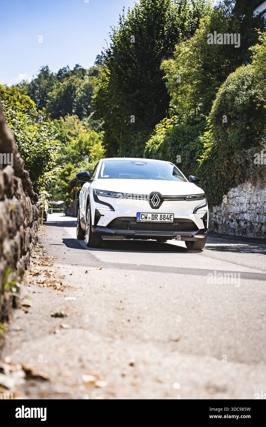 Auto su una strada soleggiata circondata da verde natura e foresta, Deer e-Carsharing, Renault Megane, Calw, Germania Foto Stock