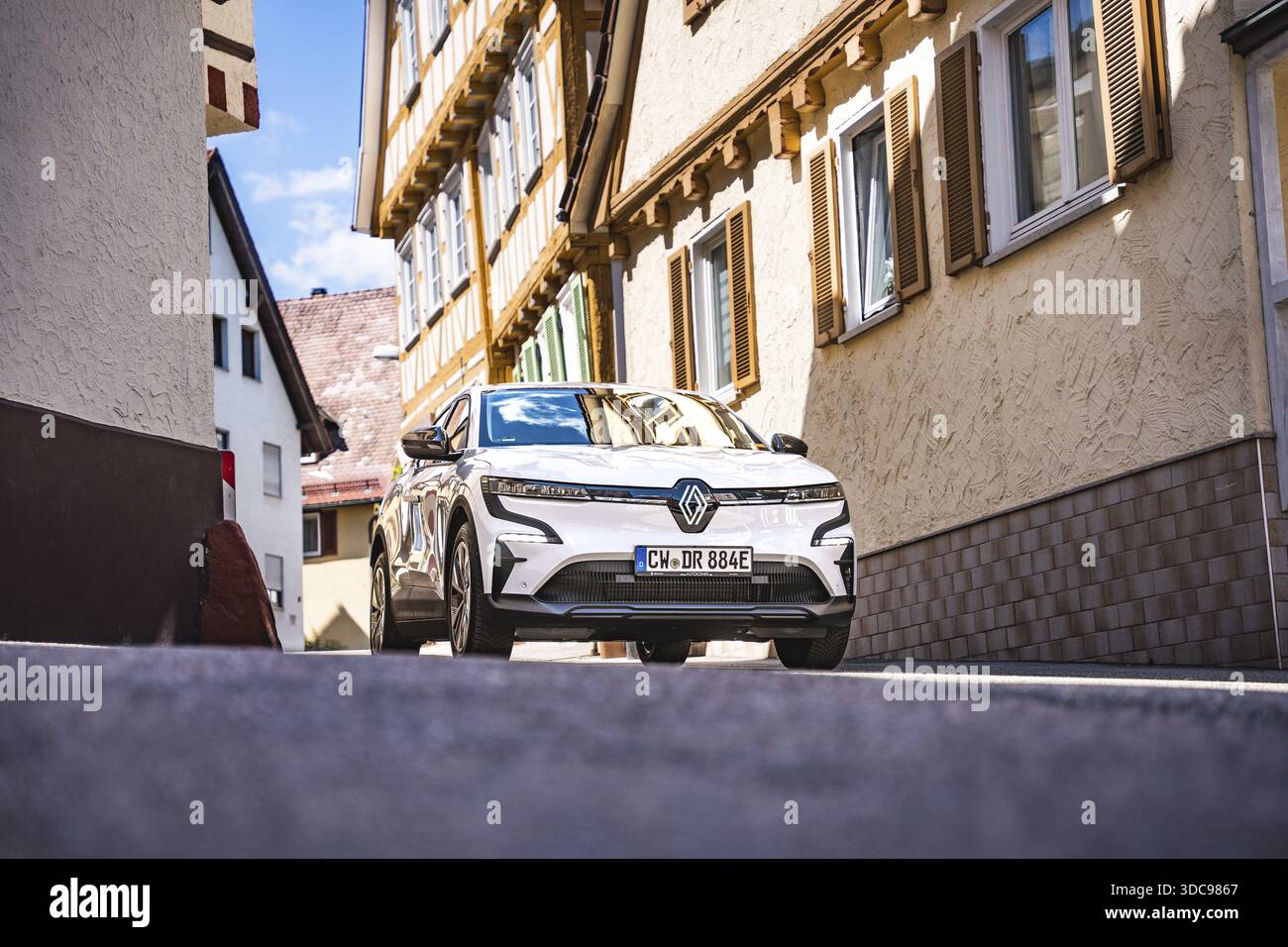 Renault su una strada soleggiata tra edifici con architettura tradizionale, Deer e-car sharing, Renault Megane, Calw, Germania Foto Stock