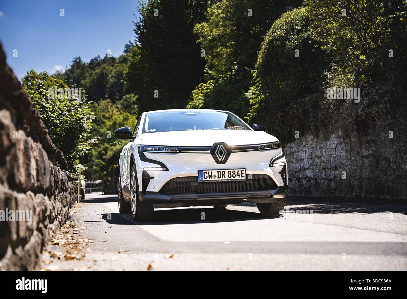 Auto bianca che percorre una strada alberata in pietra, Deer e-Carsharing, Renault Megane, Calw, Germania Foto Stock