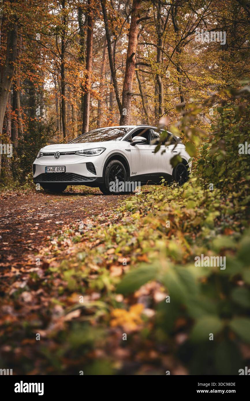 SUV in una foresta di colori autunnali su uno stretto sentiero, Deer e-Carsharing, VW ID4, Calw, Germania Foto Stock