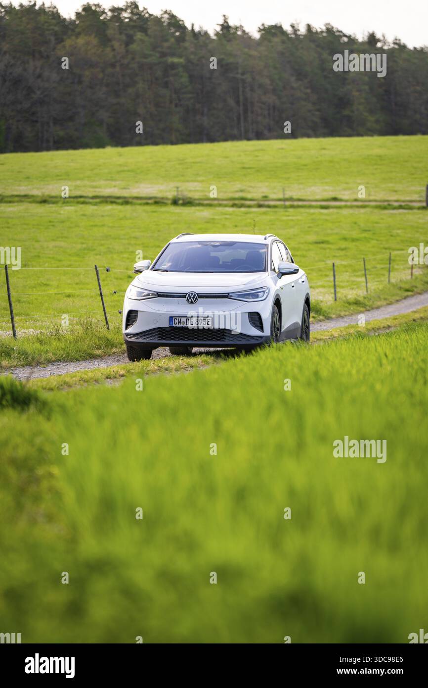 SUV su un percorso tra vasti campi verdi, condivisione di auto elettriche con cervi, VW ID4, Calw, Germania Foto Stock