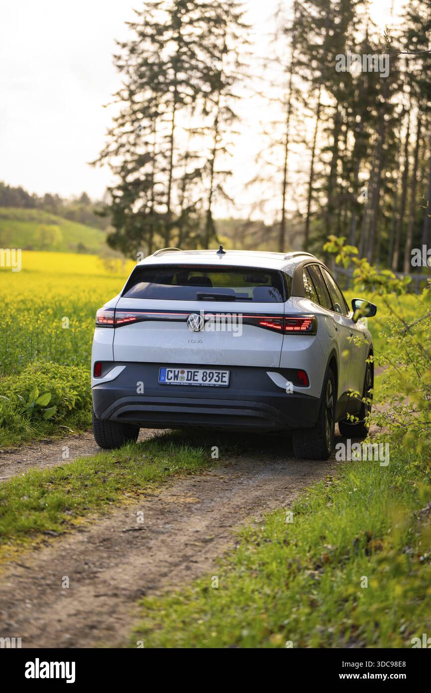 SUV che viaggia su un sentiero rurale circondato da campi verdi, e-car per cervi, VW ID4, Calw, Germania Foto Stock