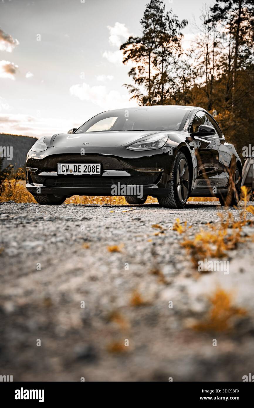 Black Tesla su strada sterrata al tramonto in ambiente naturale, e-car sharing Deer, Tesla Model 3, Calw, Germania Foto Stock