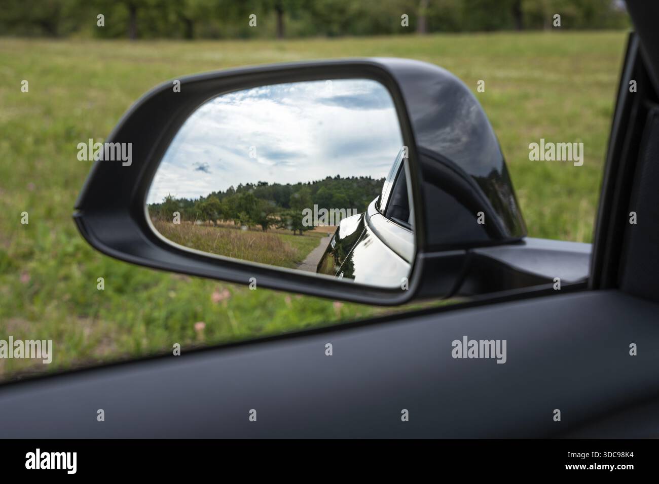 Vista di una strada rurale e di una foresta attraverso lo specchio dell'auto, e-car sharing Deer, Tesla Model 3, Calw, Germania Foto Stock
