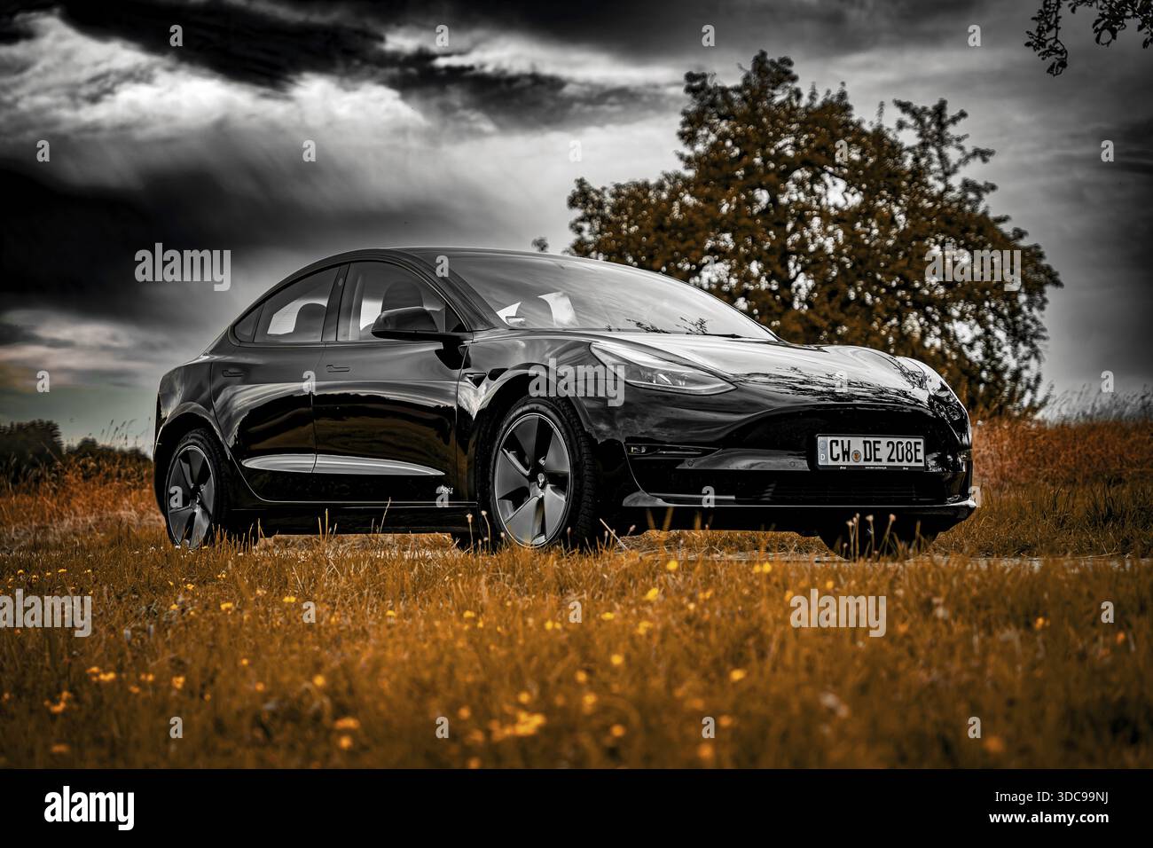 Auto nera parcheggiata su strada di campagna, nuvole spettacolari nel cielo circondati da prati, Deer e-Carsharing, Tesla Model 3, Calw, Germania Foto Stock