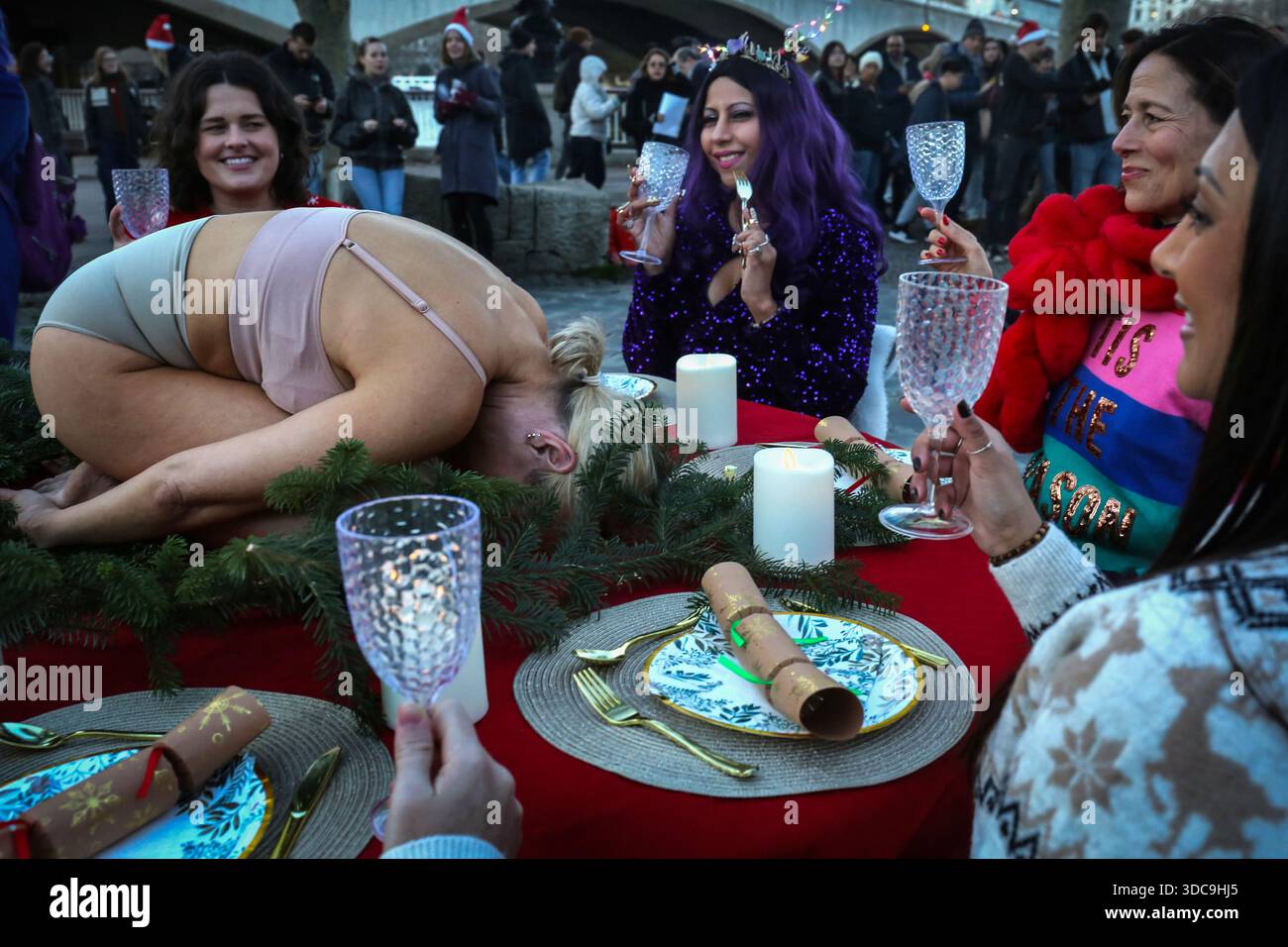 Londra, Regno Unito. 20 dicembre 2025. Un uomo si arriccia al posto del solito tacchino su un tavolo di Natale decorato, circondato da cene. Il movimento artistico globale vegano "SpeciesismWTF" ha creato un'installazione artistica sulla South Bank di Londra. L'opera d'arte, intitolata "il pollame non è umano(e)", colloca un essere umano nella posizione di un animale al tavolo della cena di Natale. Essi affermano che, a livello globale, miliardi di uccelli vengono confinati, mutilati e macellati ogni anno per uova e carne. Credito: SOPA Images Limited/Alamy Live News Foto Stock