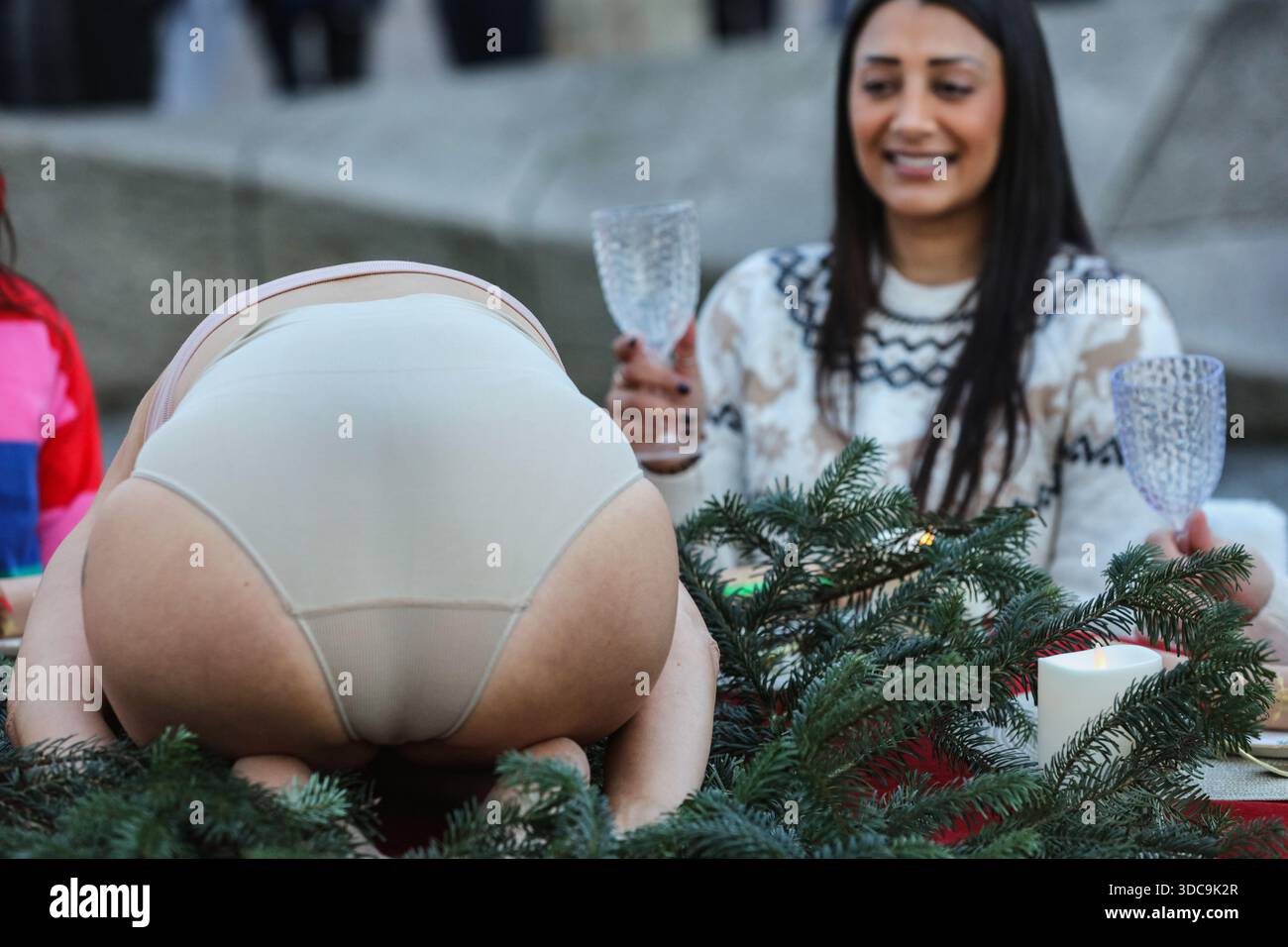 Londra, Regno Unito. 20 dicembre 2025. Un commensale solleva i bicchieri come un essere umano viene presentato sul tavolo al posto del pollame durante l'installazione. Il movimento artistico globale vegano "SpeciesismWTF" ha creato un'installazione artistica sulla South Bank di Londra. L'opera d'arte, intitolata "il pollame non è umano(e)", colloca un essere umano nella posizione di un animale al tavolo della cena di Natale. Essi affermano che, a livello globale, miliardi di uccelli vengono confinati, mutilati e macellati ogni anno per uova e carne. (Foto di Martin Pope/SOPA Images/Sipa USA) credito: SIPA USA/Alamy Live News Foto Stock