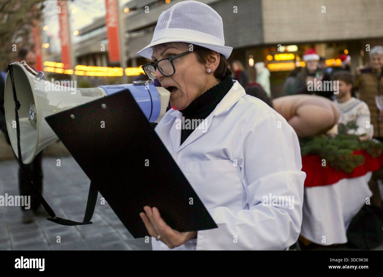 Londra, Regno Unito. 20 dicembre 2025. Un agricoltore con un appunti racconta ai passanti della loro azienda che allevano esseri umani per il consumo presso l'impianto. Il movimento artistico globale vegano "SpeciesismWTF" ha creato un'installazione artistica sulla South Bank di Londra. L'opera d'arte, intitolata "il pollame non è umano(e)", colloca un essere umano nella posizione di un animale al tavolo della cena di Natale. Essi affermano che, a livello globale, miliardi di uccelli vengono confinati, mutilati e macellati ogni anno per uova e carne. (Foto di Martin Pope/SOPA Images/Sipa USA) credito: SIPA USA/Alamy Live News Foto Stock