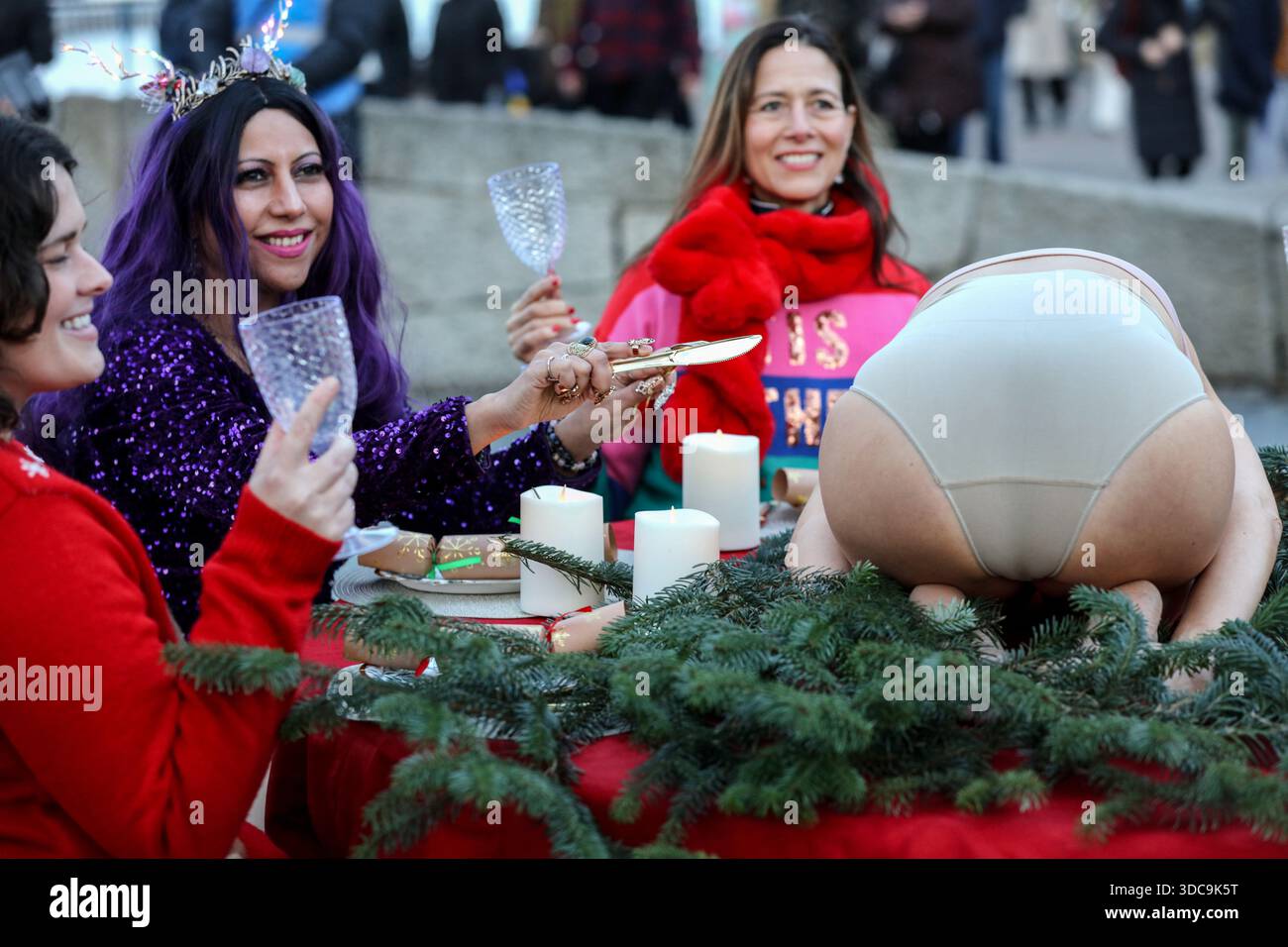 Londra, Regno Unito. 20 dicembre 2025. I commensali alzano i loro bicchieri mentre un altro si prepara a intagliare l'articolazione umana scelta al posto del pollame durante l'installazione. Il movimento artistico globale vegano "SpeciesismWTF" ha creato un'installazione artistica sulla South Bank di Londra. L'opera d'arte, intitolata "il pollame non è umano(e)", colloca un essere umano nella posizione di un animale al tavolo della cena di Natale. Essi affermano che, a livello globale, miliardi di uccelli vengono confinati, mutilati e macellati ogni anno per uova e carne. (Foto di Martin Pope/SOPA Images/Sipa USA) credito: SIPA USA/Alamy Live News Foto Stock