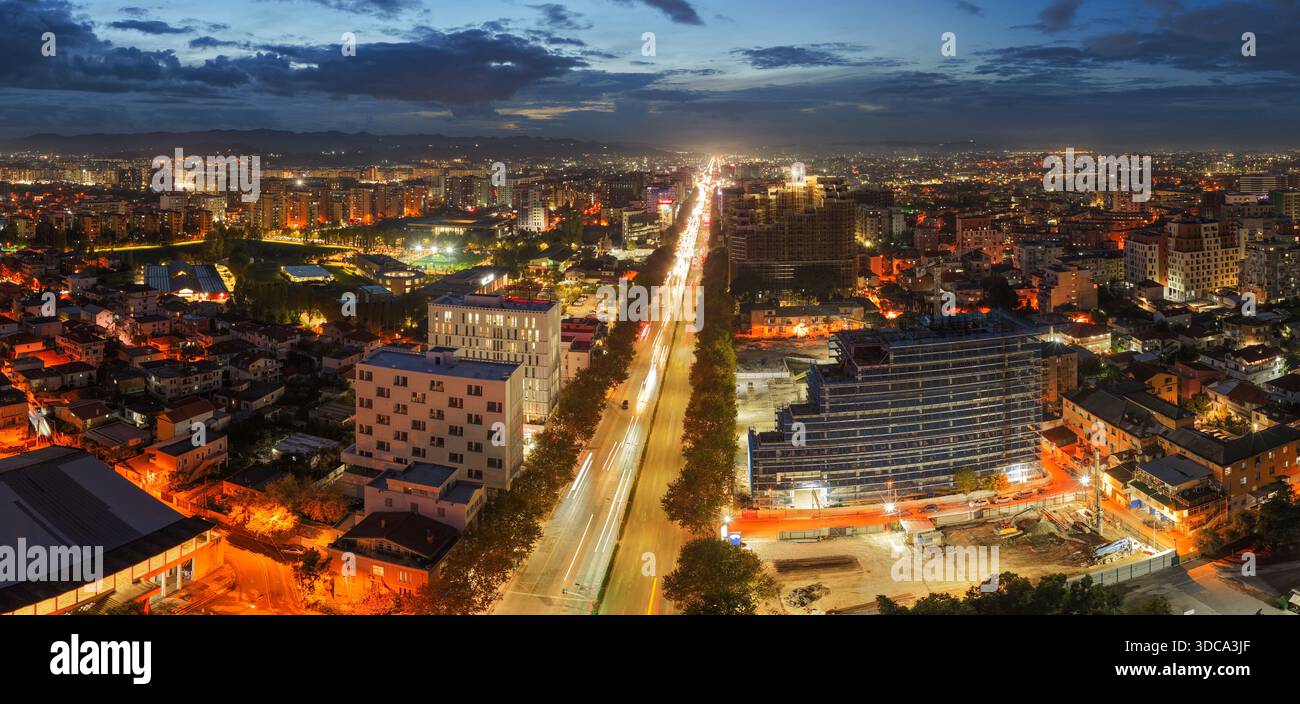 Vista aerea del tramonto su Tirana, che mostra Zogu i Zi e lo skyline occidentale della città illuminata da calde luci urbane. Foto Stock