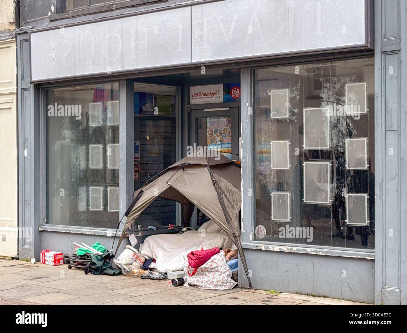 Bridgend, Galles, Regno Unito - 14 dicembre 2025: Tenda e oggetti di una senzatetto rude dormiente all'ingresso di un negozio chiuso nel centro di Bridgend. - Immagine stock catturata con smartphone