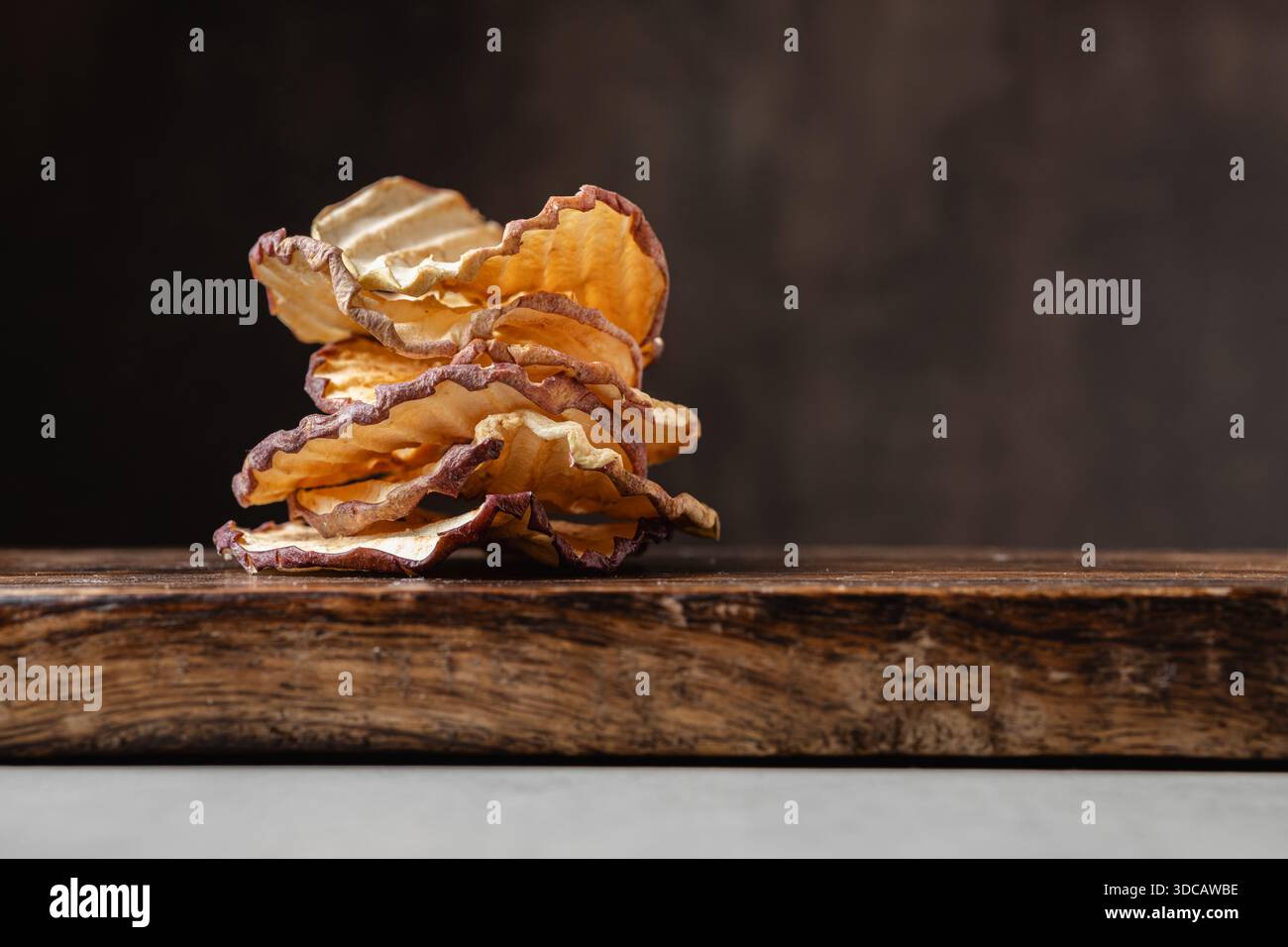 Chip di mele su sfondo scuro. Uno spuntino sano e delizioso pieno di vitamine. Adatto per vegetariani. Foto Stock