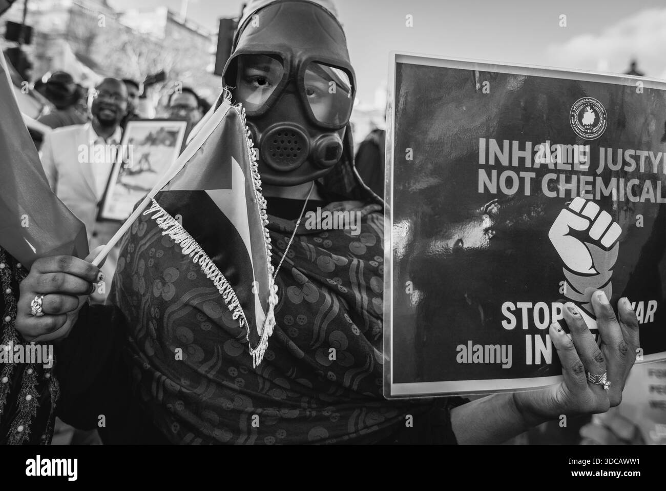 Un'immagine in bianco e nero di attivisti mascherati della crisi del Sudan durante una protesta a Londra. Foto Stock