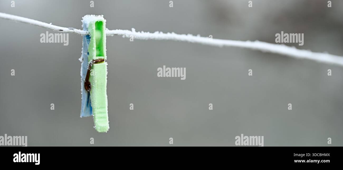 Brina su appendiabiti di plastica lasciati su una linea di lavaggio in inverno, modulo per striscioni Foto Stock