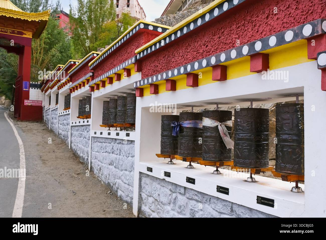 Movimento rituale e ripetizione, ruote di preghiera che costeggiano il percorso d'ingresso di un monastero buddista tibetano a Ladakh, Himalaya, India. Foto Stock