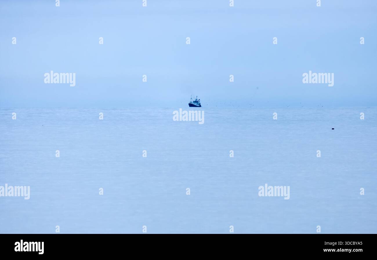 Lontano tiro di una barca da pesca blu su un mare blu calmo Foto Stock