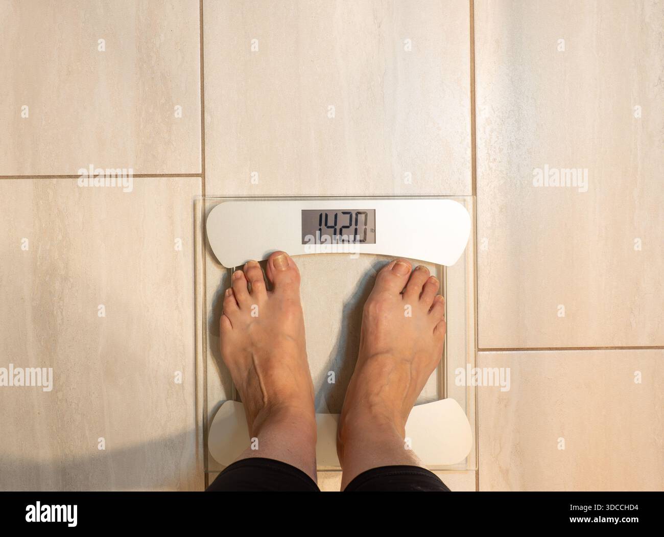 Donna anziana con leggings neri e in piedi su una bilancia da bagno, con un peso di 142 kg. Foto Stock
