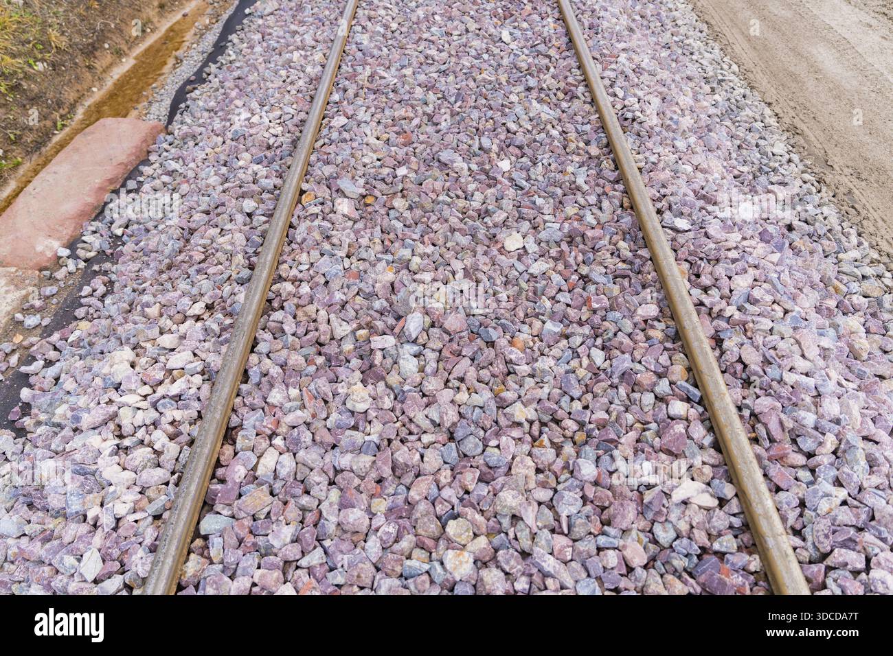 Primo piano di binari ferroviari ricoperti di ghiaia grigia e viola, costruzione della ferrovia Hermann Hesse, Calw, Germania Foto Stock