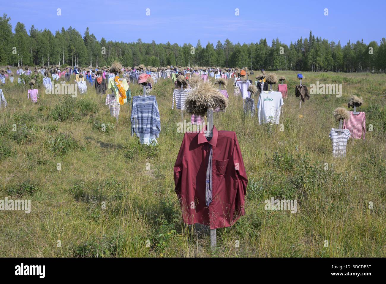 Opere d'arte installazione all'aperto la gente silenziosa delle bambole Reijo Kela Straw indossa abiti colorati in un campo ai margini della foresta, Suomussalmi, Kain Foto Stock