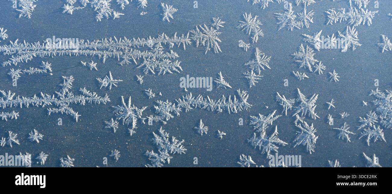 Piccoli cristalli di ghiaccio bianchi sulla lamiera di metallo grigia di un'auto, forma striscione Foto Stock