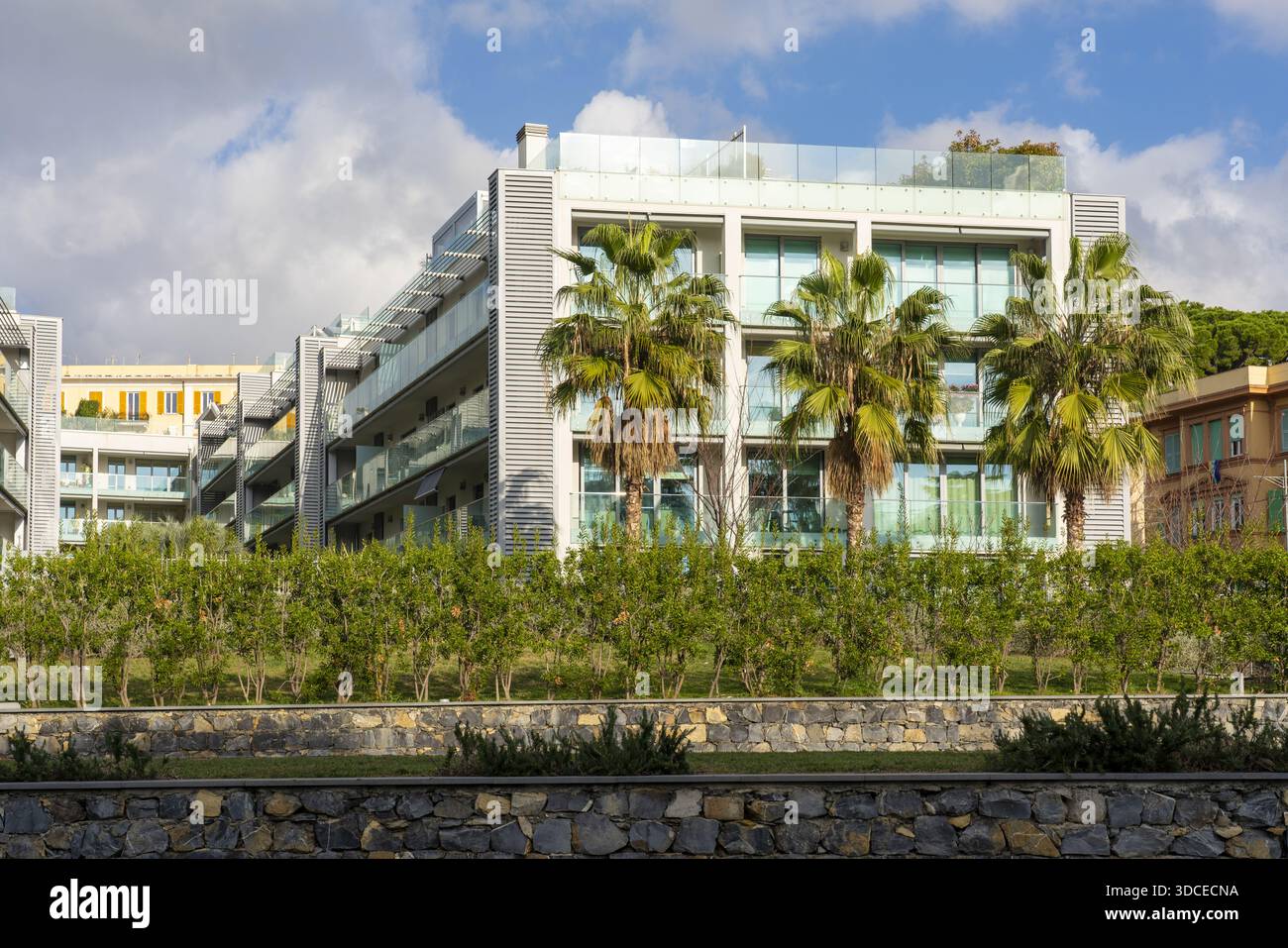La vista di edifici moderni con palme crea un contrasto sorprendente con il cielo limpido, mescolando architettura urbana con vibrazioni tropicali, Genova, Lig Foto Stock