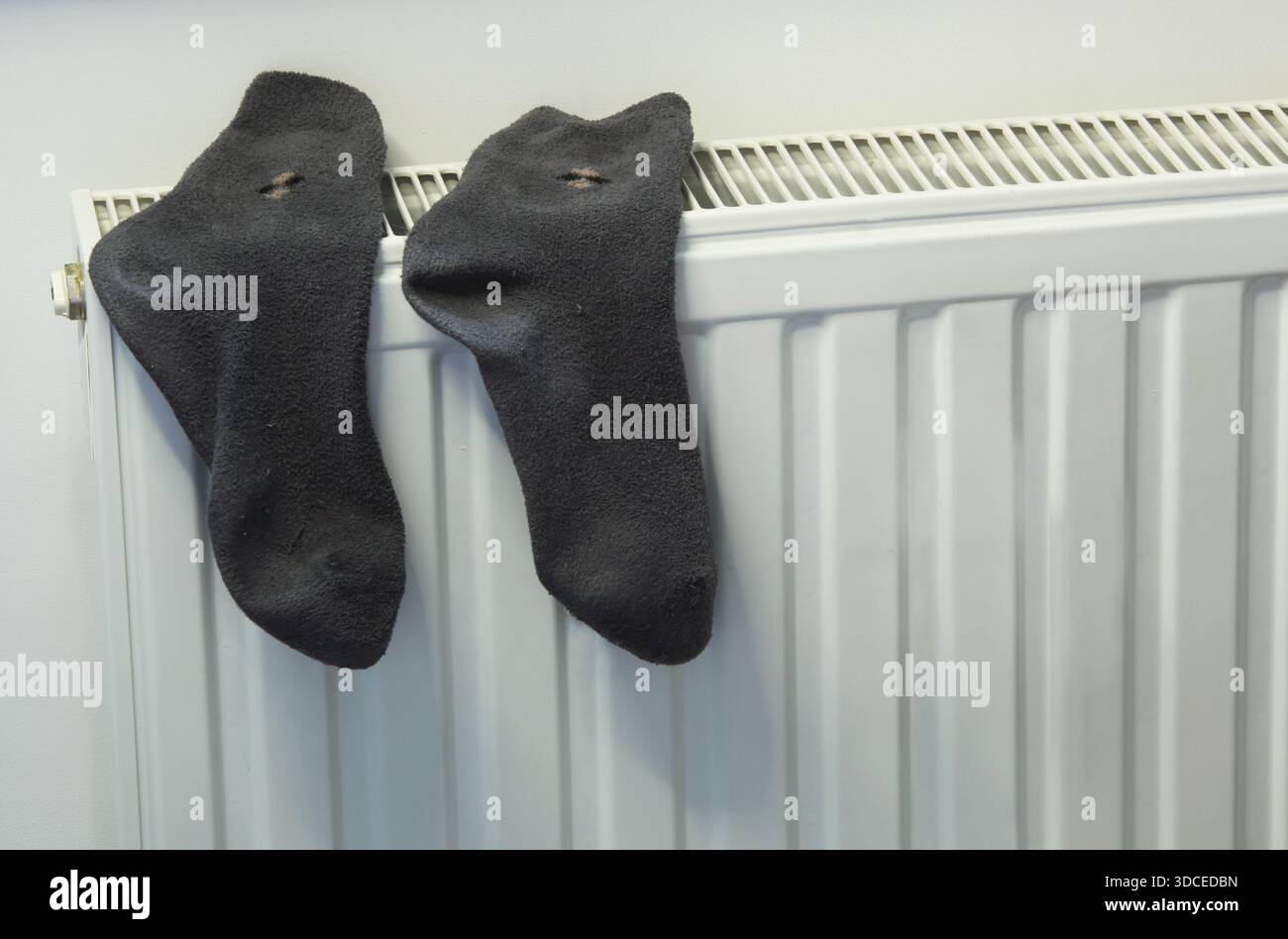 Un ambiente domestico di tutti i giorni con calze scure appese su un moderno radiatore. Il concetto di comfort domestico, risparmio energetico, asciugatura. Foto Stock