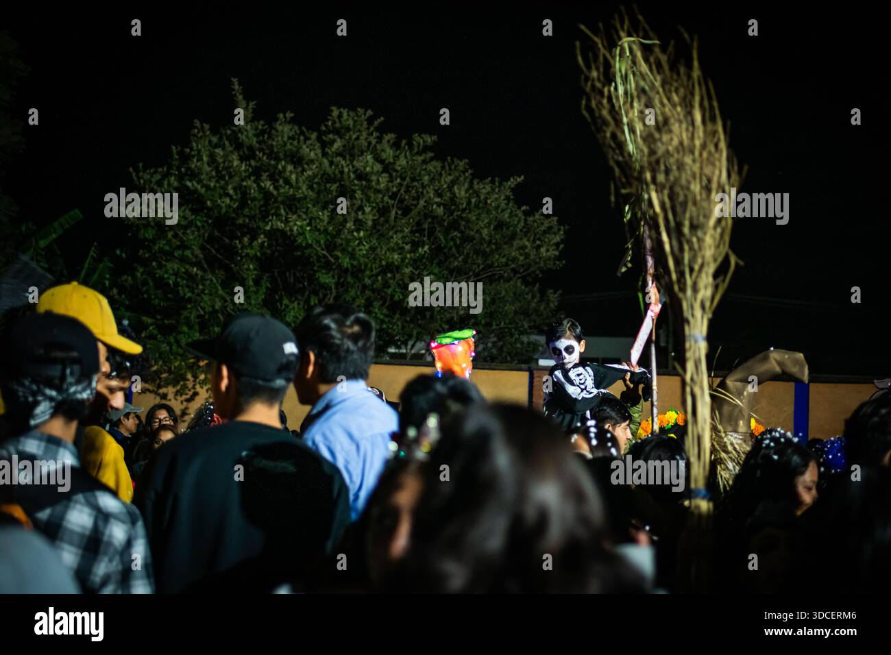 Santa Maria del Tule, Messico - 3 novembre 2023: Veduta di un bambino vestito come uno scheletro tra la folla, che tiene una scopa, nel cementar del giorno della morte Foto Stock