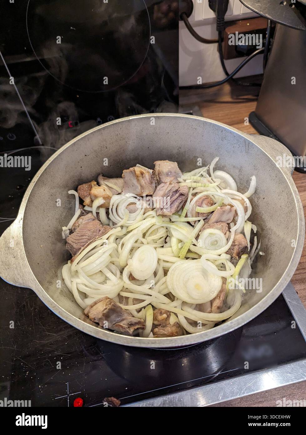 Pforzheim, Germania Dezember affettato di carne con anelli di cipolla crudi in pentola pesante, spremute e doratura dei bordi, saute preparatorie Foto Stock