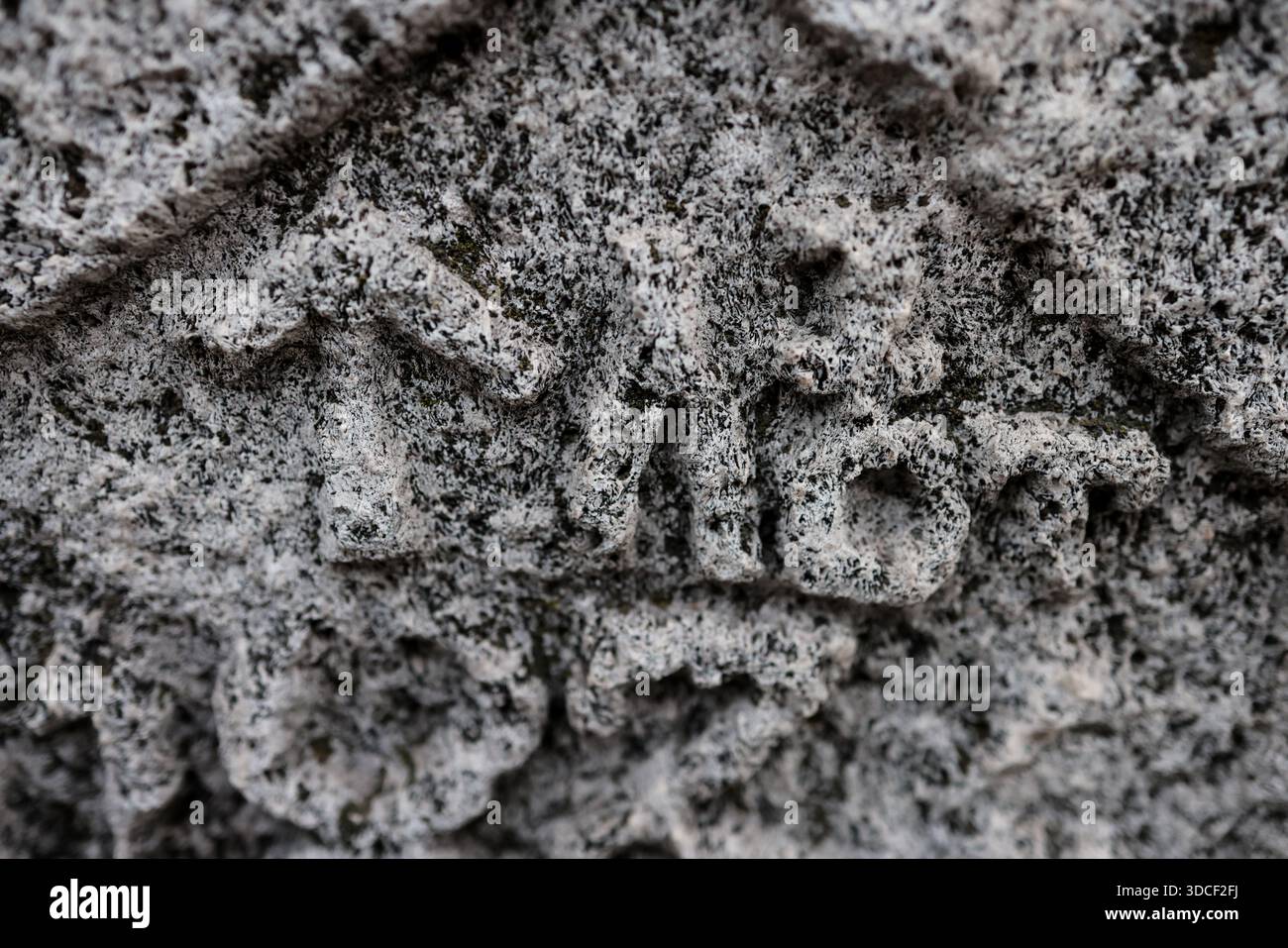 Profondità di campo bassa (messa a fuoco selettiva) dettagli con iscrizioni e consistenza di una vecchia croce cristiana ortodossa in pietra. Foto Stock