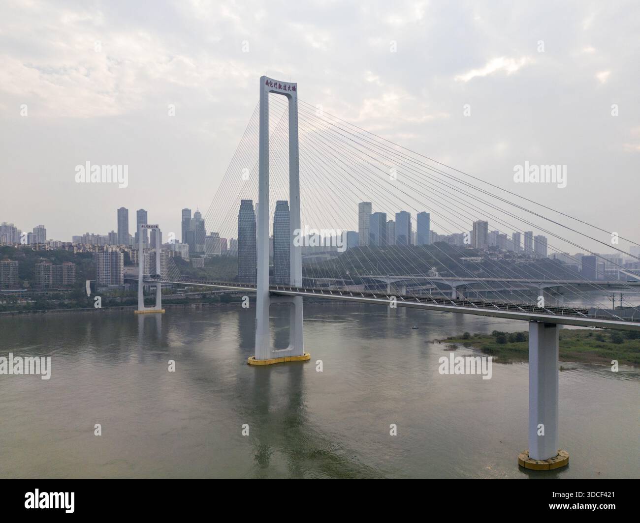 Veduta aerea dell'impressionante ponte sospeso bianco in contrasto con lo skyline della città e il fiume che scorre, Chongqing, Chongqing, Cina. Foto Stock