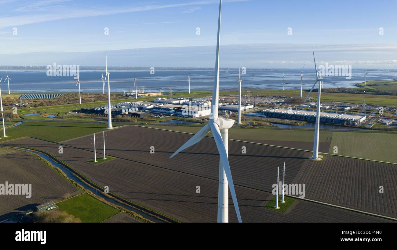 Vista aerea di un grande datacenter che consuma energia alimentato da turbine eoliche e pannelli solari nelle vicinanze, evidenziando la produzione e il mod di energia sostenibile Foto Stock