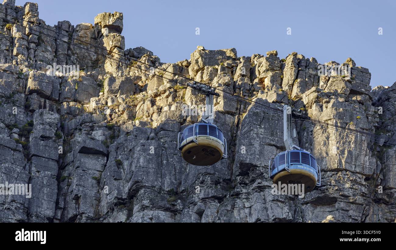 Città del Capo, Sud Africa - 25 novembre 2025: Vista delle funivie che si arrampicano contro l'aspra struttura della Table Mountain, bagnata dalla luce soffusa del sole. Foto Stock