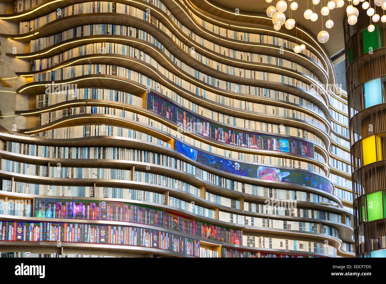 Vista di una libreria ricurva piena di innumerevoli volumi, illuminata da luci calde e display colorati, per creare un letterario coinvolgente Foto Stock