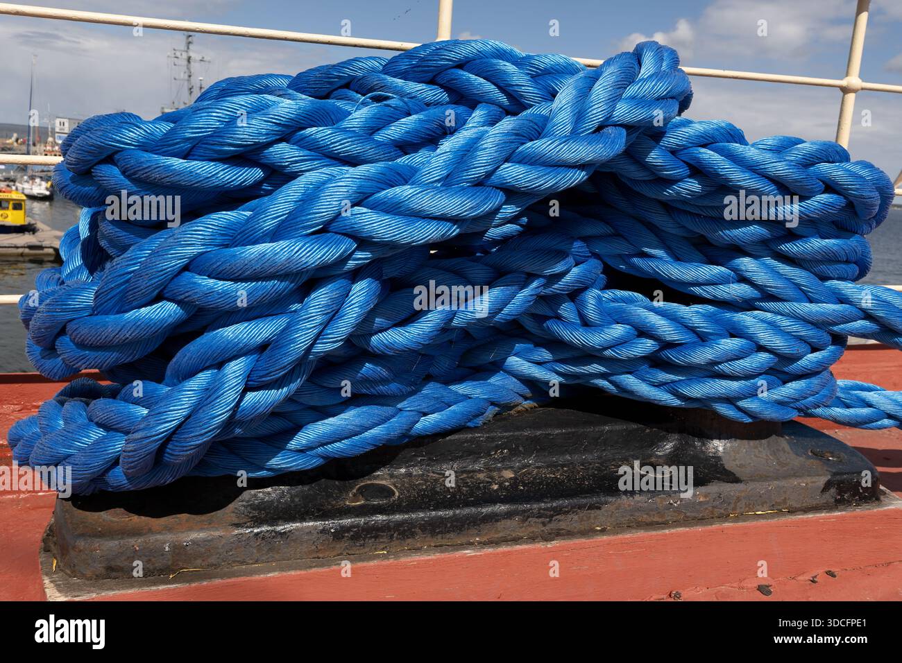 Fune di ormeggio blu per impieghi gravosi arrotolata sul ponte della nave. Foto Stock