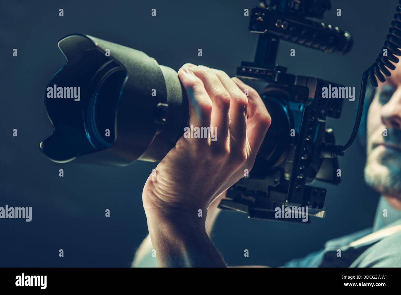 Una persona tiene in mano una fotocamera con un obiettivo grande in uno studio. Foto Stock