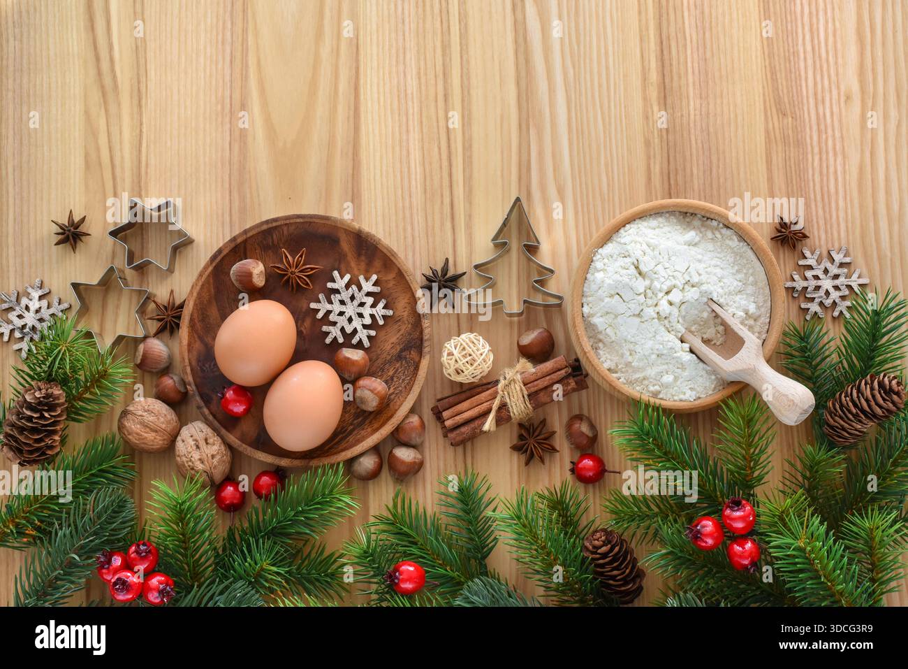 Preparazione per la cottura delle feste con uova, farina, noci e rami di abete rosso su un tavolo di legno. Vista dall'alto. Con spazio per il testo Foto Stock