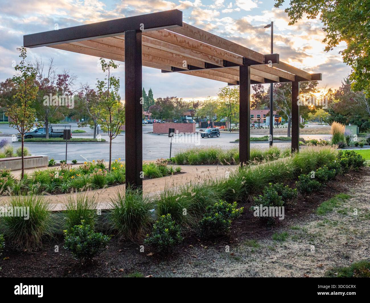La vista di un pergolato moderno getta ombre sui curati letti del giardino lungo il parcheggio di Apollo Park, Hillsboro, Oregon, Stati Uniti. Foto Stock