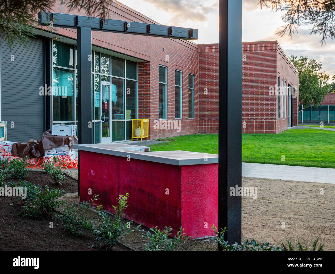 Vista di un edificio in mattoni con accenti neri, una piantatrice rossa e un fresco paesaggio che crea una scena architettonica moderna, Apollo Park, Oregon, United Foto Stock