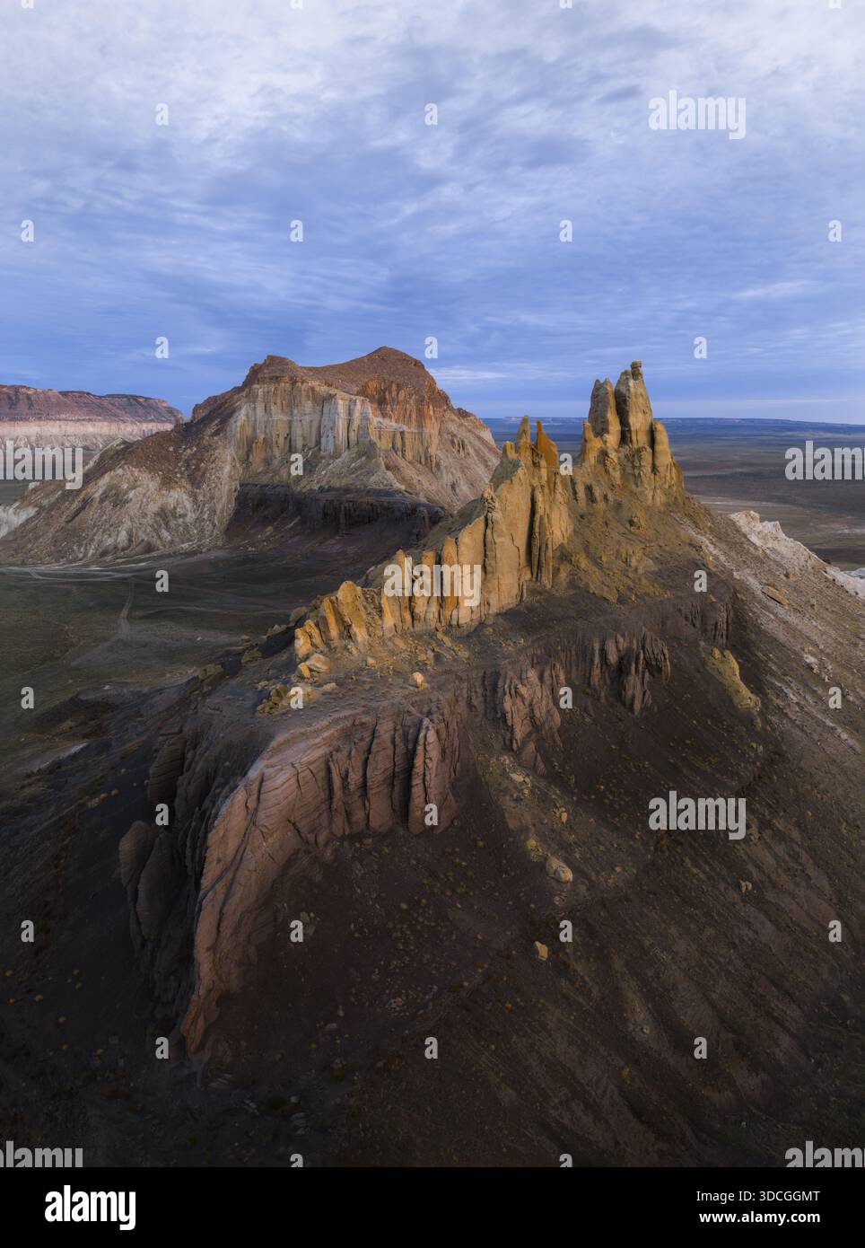 Vista aerea delle frastagliate formazioni rocciose sorgono drammaticamente dal paesaggio arido, le loro vette illuminate dal sole contrastano con le ombre profonde, Shetpe, Mangyst Foto Stock