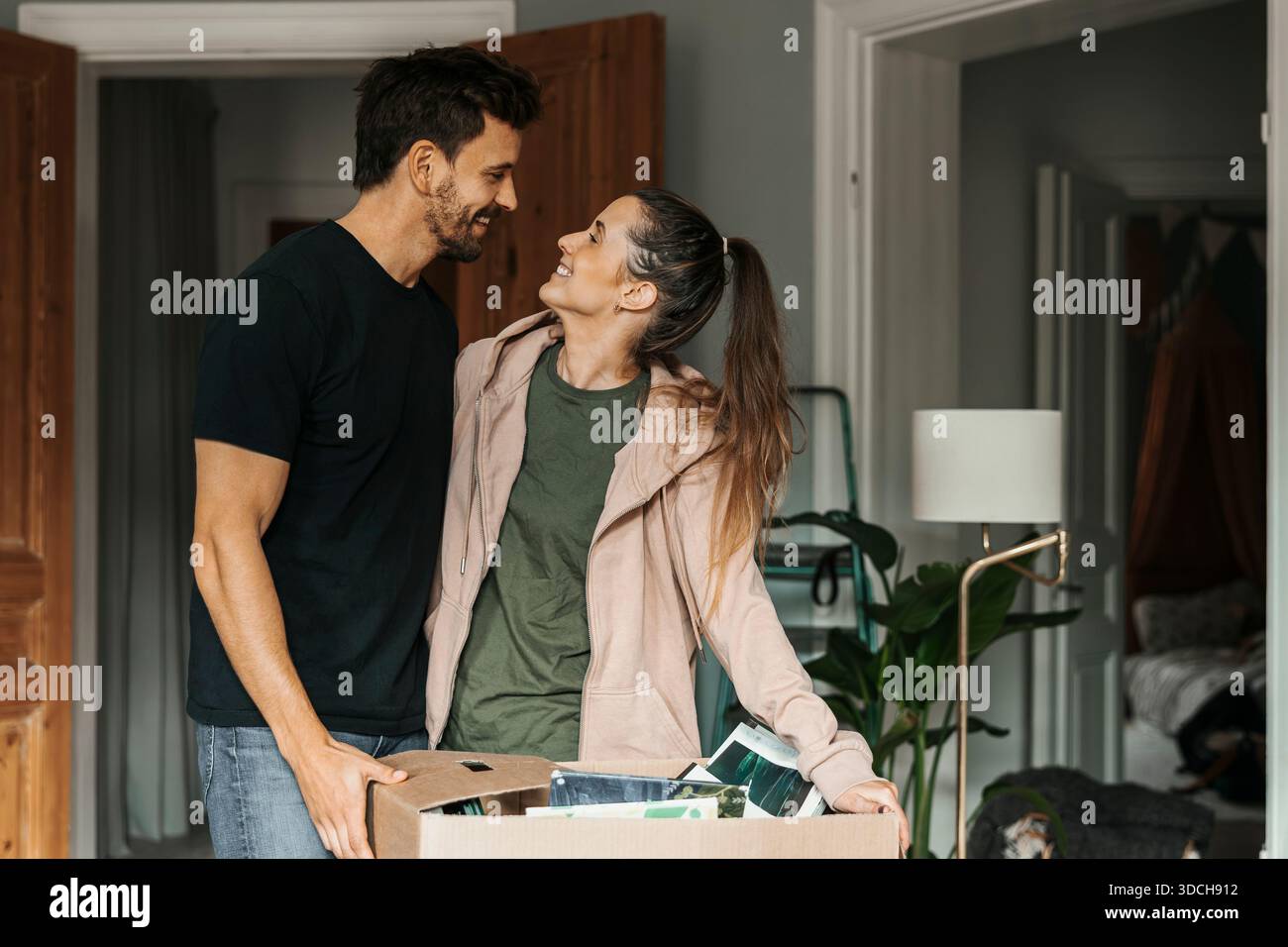Donna sorridente che passa del tempo con l'uomo nella nuova casa Foto Stock